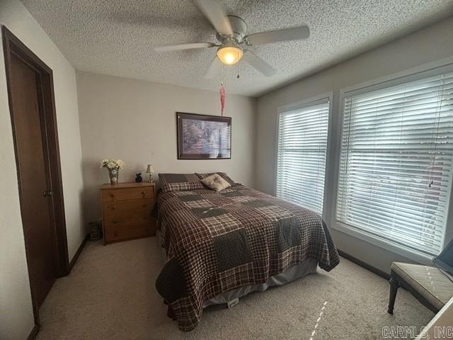 bedroom featuring light carpet, a textured ceiling, and ceiling fan