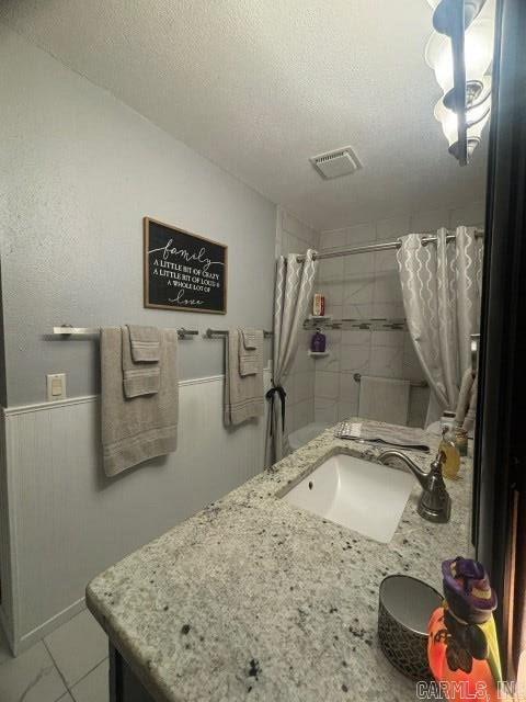 bathroom featuring a textured ceiling, vanity, and walk in shower