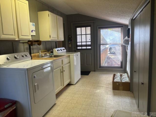 laundry area with washer and clothes dryer, cabinets, and a textured ceiling