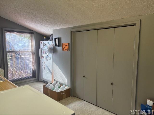 unfurnished bedroom with a textured ceiling, a closet, multiple windows, and lofted ceiling