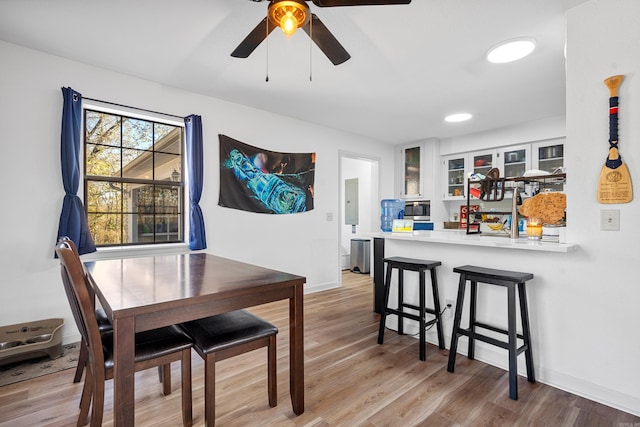 dining space featuring light wood-type flooring, electric panel, and ceiling fan