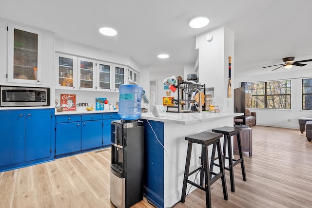 kitchen with a kitchen breakfast bar, white cabinetry, light hardwood / wood-style flooring, and blue cabinets