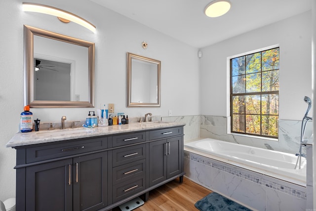 bathroom with vanity, hardwood / wood-style flooring, ceiling fan, and tiled tub