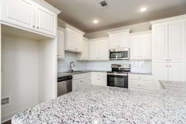 kitchen featuring tasteful backsplash, white cabinetry, sink, and appliances with stainless steel finishes