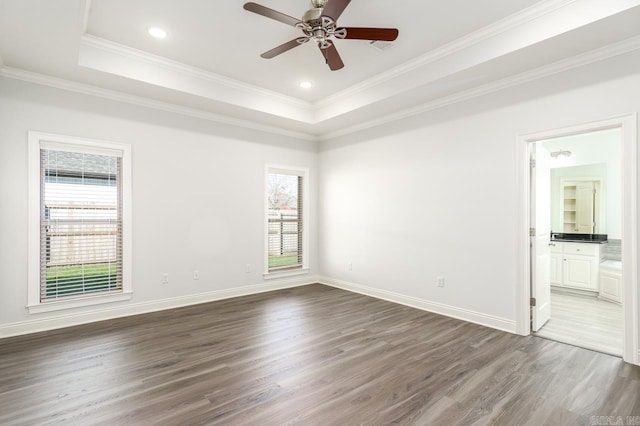 unfurnished room featuring a raised ceiling, ceiling fan, dark hardwood / wood-style flooring, and ornamental molding