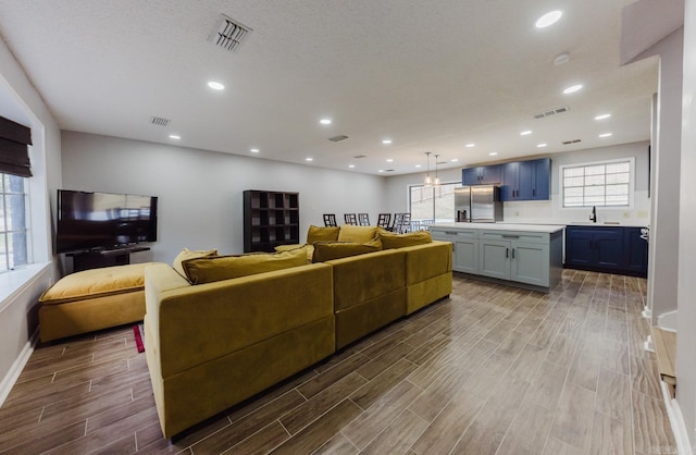 living room with sink, a textured ceiling, and light wood-type flooring