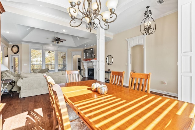 dining area featuring dark hardwood / wood-style flooring, ceiling fan with notable chandelier, a tray ceiling, and ornamental molding