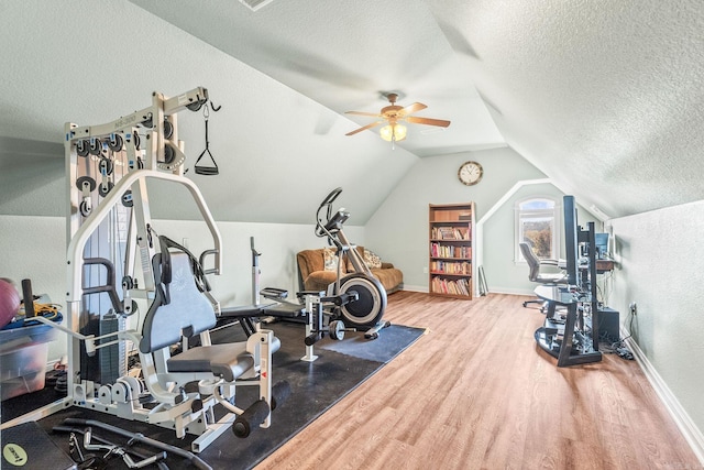 workout room with a textured ceiling, hardwood / wood-style flooring, vaulted ceiling, and ceiling fan