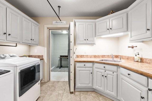 kitchen featuring white cabinets, independent washer and dryer, sink, and light tile patterned floors