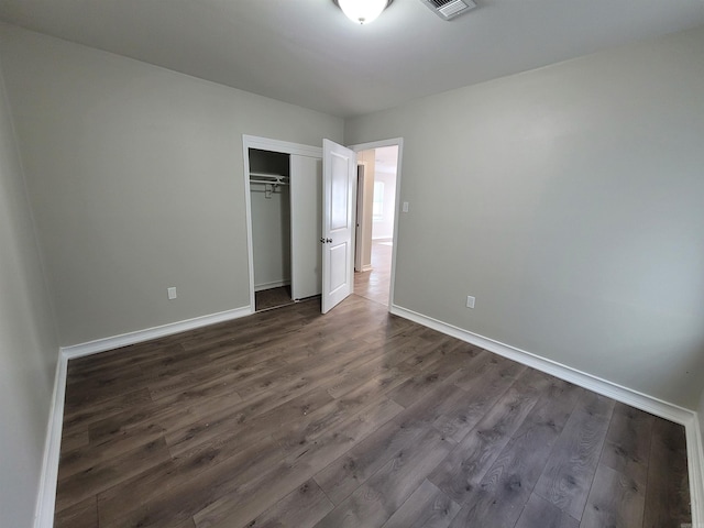 unfurnished bedroom with dark hardwood / wood-style floors and a closet