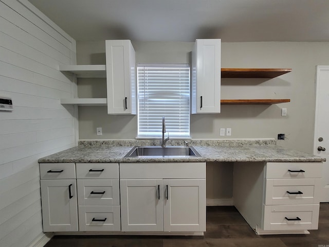 kitchen featuring wood walls, white cabinetry, and sink