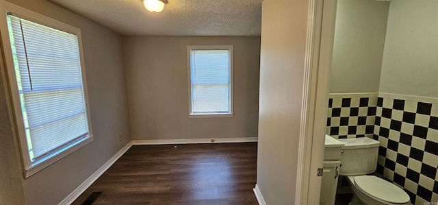 bathroom with plenty of natural light, wood-type flooring, a textured ceiling, and toilet