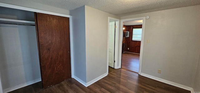 unfurnished bedroom with a textured ceiling, a closet, and dark hardwood / wood-style floors