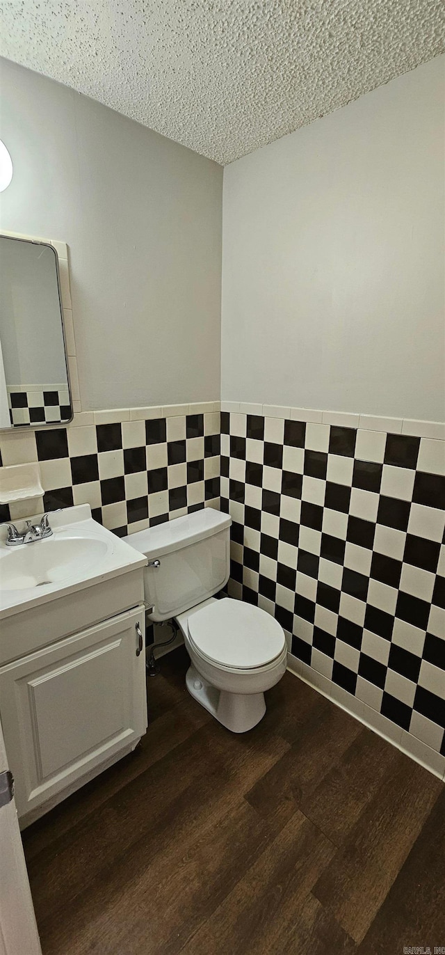 bathroom featuring hardwood / wood-style flooring, toilet, a textured ceiling, and tile walls