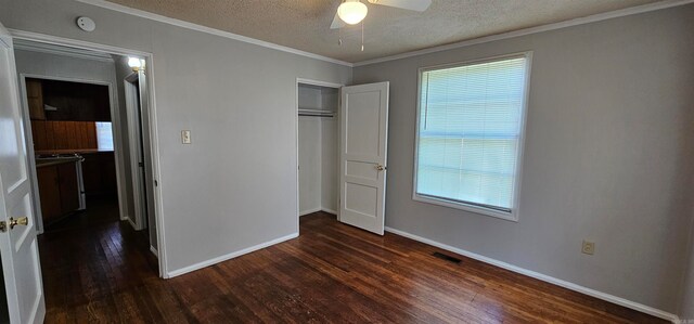 unfurnished bedroom with ceiling fan, dark wood-type flooring, crown molding, a textured ceiling, and a closet