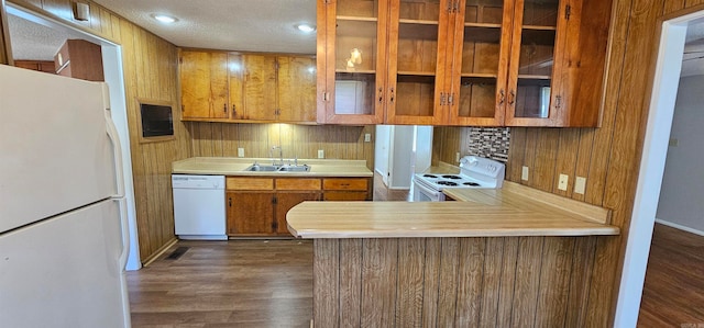 kitchen with sink, dark wood-type flooring, kitchen peninsula, a textured ceiling, and white appliances