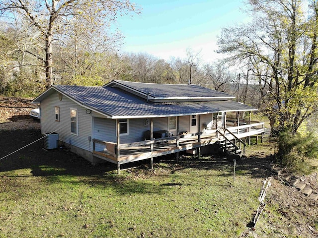 rear view of house featuring central air condition unit, a wooden deck, and a yard