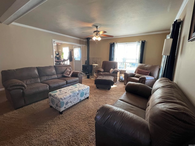 living room with a wood stove, crown molding, carpet floors, and ceiling fan