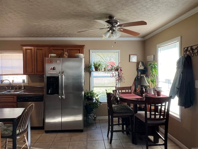 kitchen featuring a textured ceiling, stainless steel appliances, crown molding, sink, and light tile patterned floors