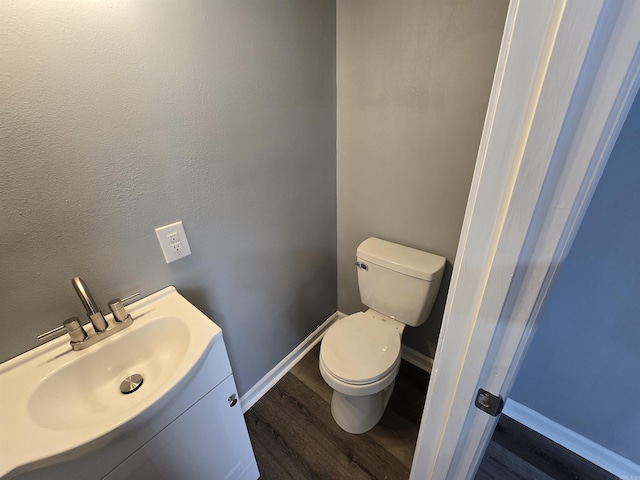 1903 W 24th Ave, Pine Bluff, AR 71603 - bathroom with wood finished floors, toilet, baseboards, and vanity