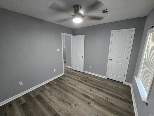 unfurnished bedroom featuring a textured ceiling, dark hardwood / wood-style flooring, and ceiling fan