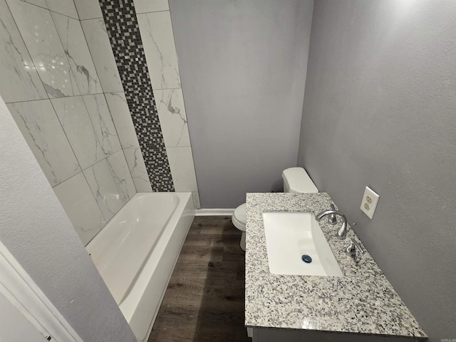 1903 W 24th Ave, Pine Bluff, AR 71603 - bathroom with wood finished floors, toilet, vanity, baseboards, and tub / shower combination