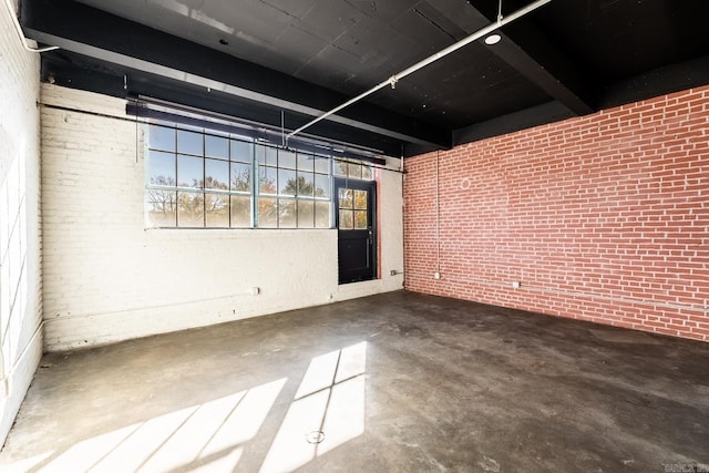 spare room featuring concrete flooring and brick wall