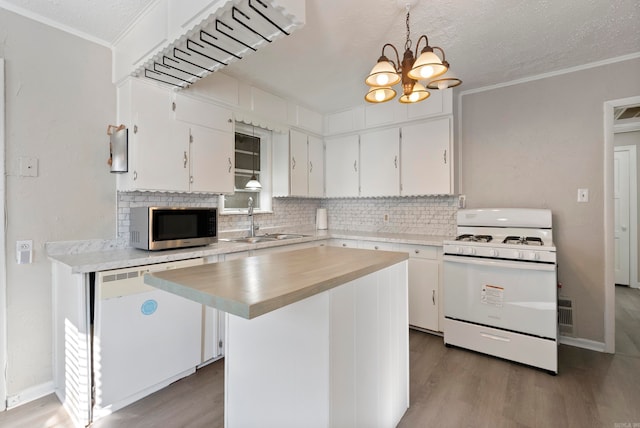 kitchen with an inviting chandelier, a kitchen island, decorative light fixtures, white appliances, and white cabinets