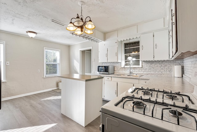 kitchen featuring decorative light fixtures, an inviting chandelier, white range oven, and white cabinetry