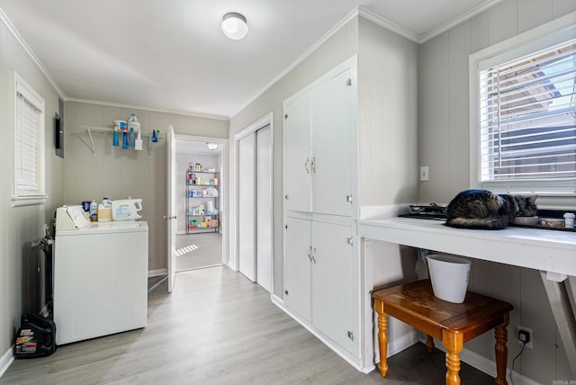 clothes washing area with washer / clothes dryer, light hardwood / wood-style flooring, and crown molding