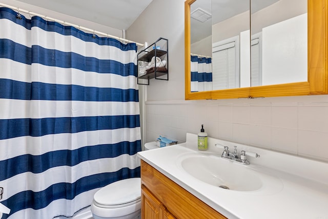 bathroom with tasteful backsplash, vanity, tile walls, toilet, and curtained shower