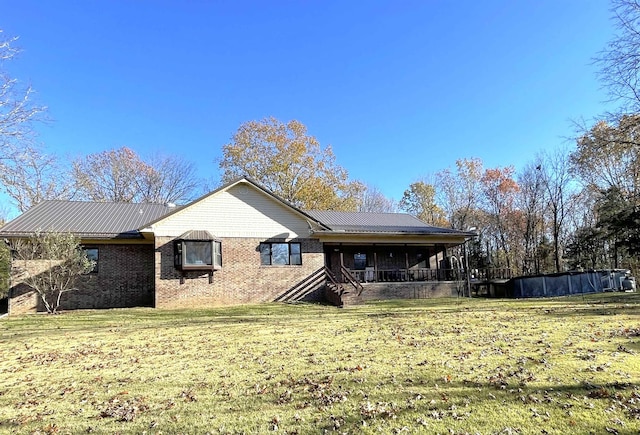 back of house with metal roof, brick siding, and a lawn