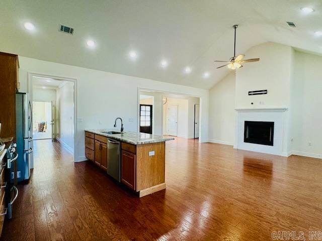 kitchen featuring appliances with stainless steel finishes, dark hardwood / wood-style flooring, light stone counters, sink, and lofted ceiling