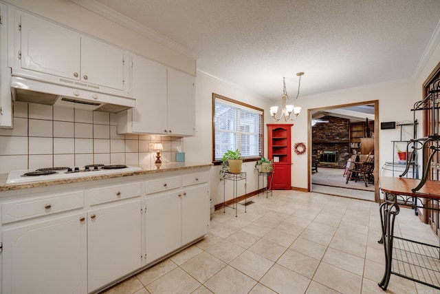 kitchen featuring tasteful backsplash, a brick fireplace, a textured ceiling, decorative light fixtures, and white cabinetry