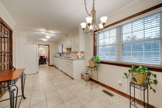 kitchen featuring white fridge, white cabinetry, crown molding, and tasteful backsplash