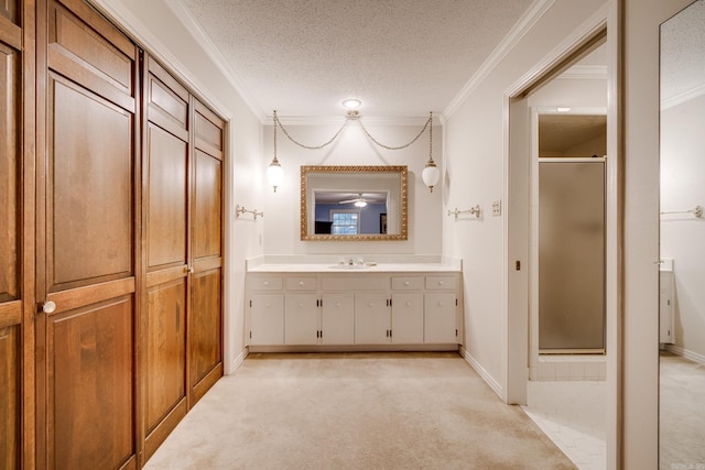 bathroom with vanity, ornamental molding, a textured ceiling, and walk in shower