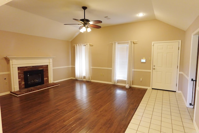 unfurnished living room with ceiling fan, a fireplace, light hardwood / wood-style floors, and vaulted ceiling