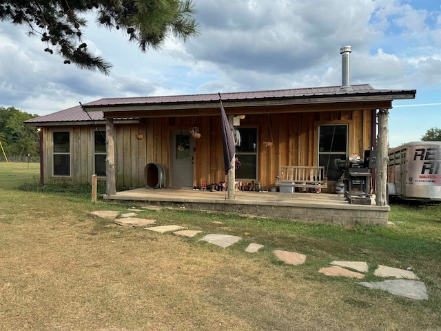 rear view of house featuring covered porch and a yard