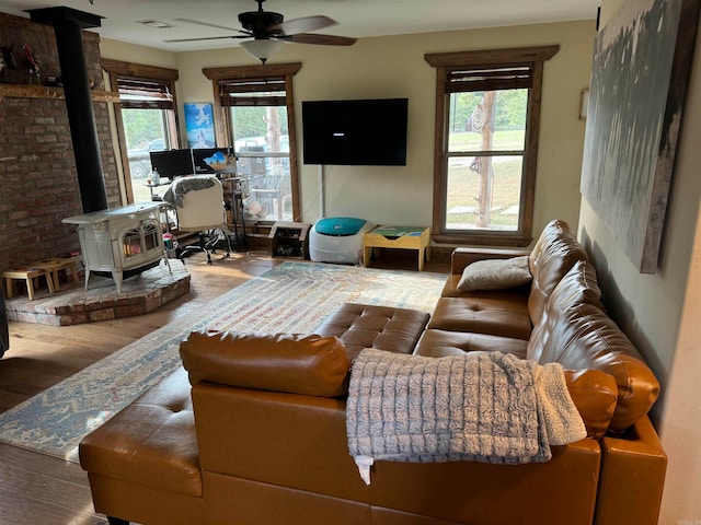 living room with ceiling fan, wood-type flooring, and a wood stove