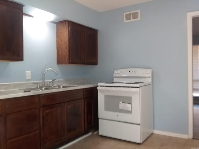 kitchen featuring white range with electric stovetop, sink, light tile patterned floors, and dark brown cabinets