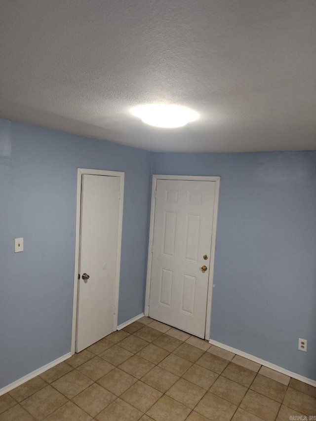 tiled empty room with a textured ceiling