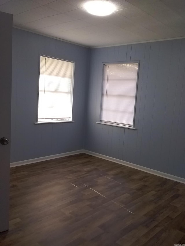 spare room featuring dark hardwood / wood-style floors and wood walls