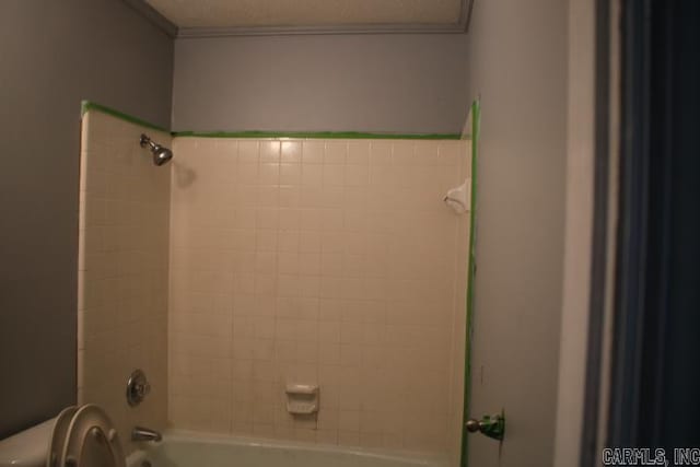 bathroom featuring tiled shower / bath combo and toilet