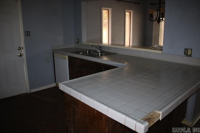 kitchen with dishwasher, tile counters, an inviting chandelier, and sink