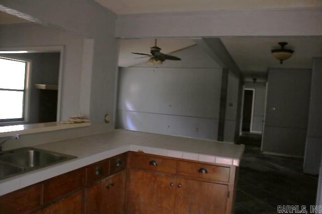 kitchen featuring kitchen peninsula, ceiling fan, and sink