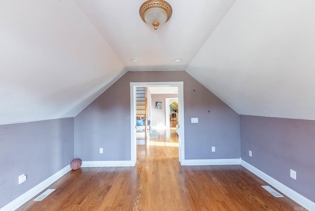 additional living space with light hardwood / wood-style floors and vaulted ceiling