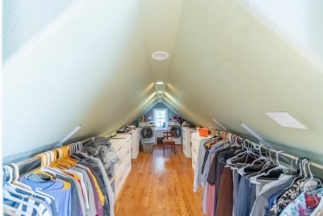 walk in closet with light wood-type flooring, lofted ceiling, and washer / dryer