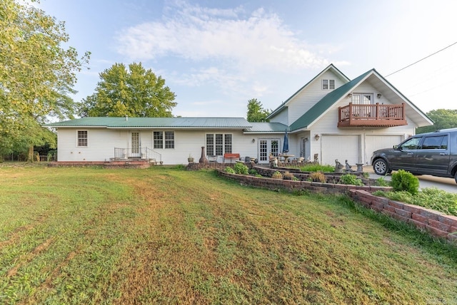 back of property with french doors, a garage, and a lawn