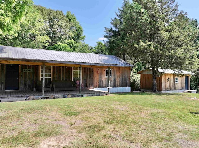 view of front of house featuring covered porch, a shed, and a front lawn