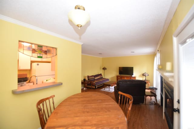 dining space featuring hardwood / wood-style floors, crown molding, and sink